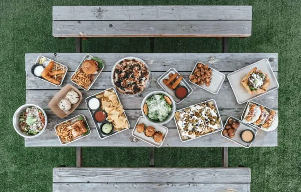 picnic table with lots of various plates of food. poolside snacks for summer days