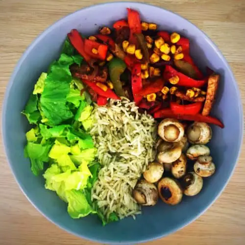 bowl with sliced lettuce, peppers, corn, mushrroms, and tempeh