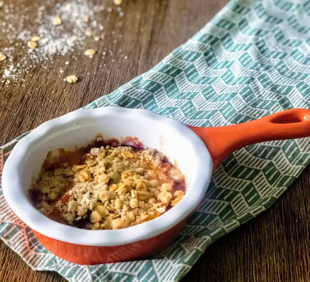 fresh peach and oat crumble in an orange baking dish